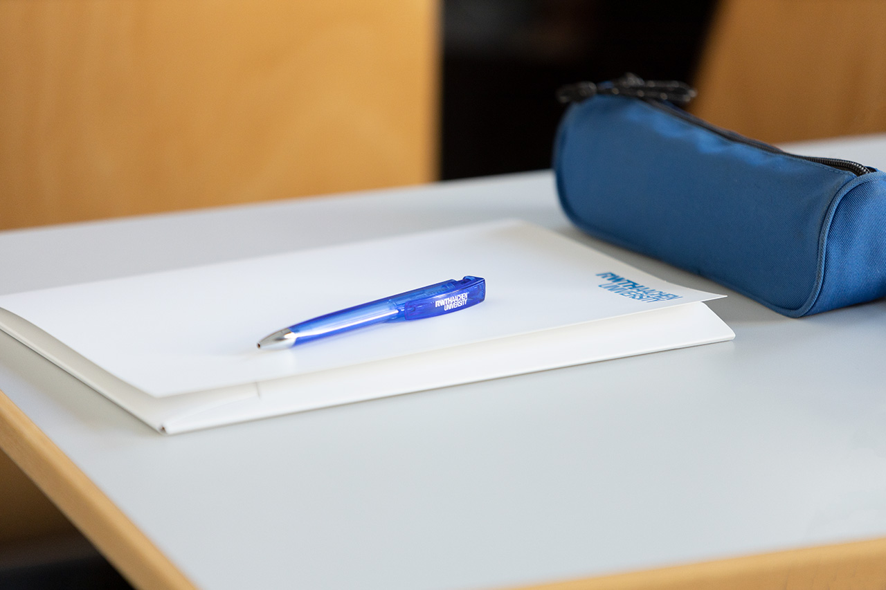 A folder, pen and pencil tray lay on a table.