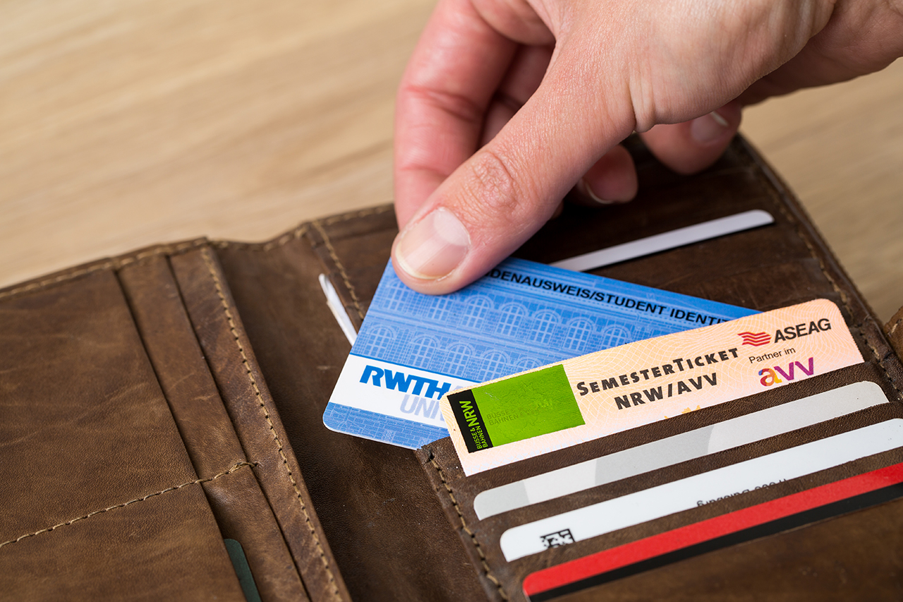 A hand is picking up RWTH Aachen student card from a purse, some other cards are also visible in the purse, e.g., Semester tichter for NRW/AVV..